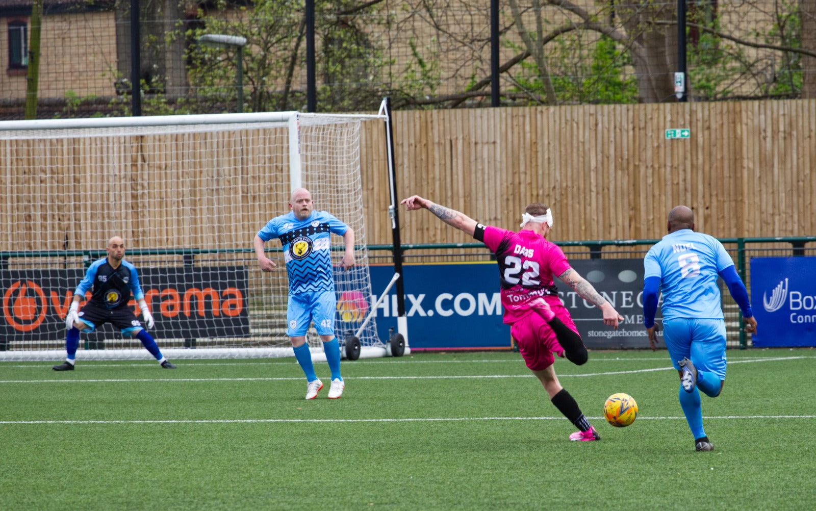 Football player in a pink and black kit during a match