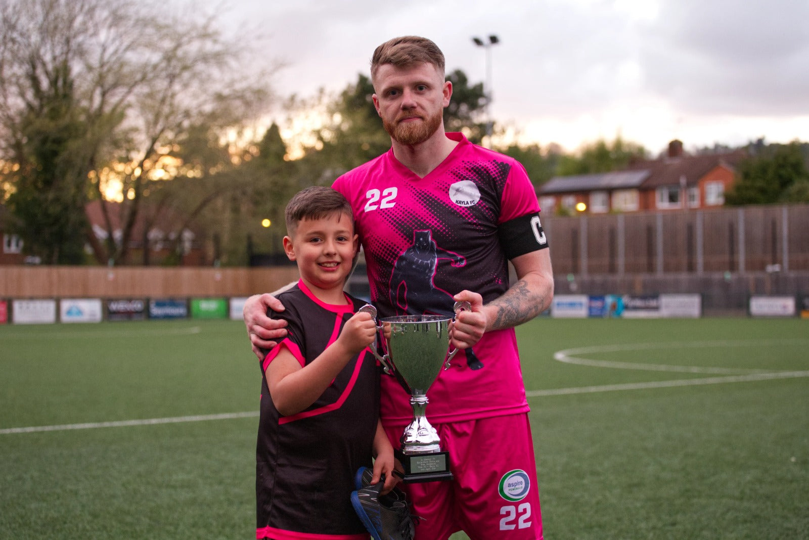 Football player and young supporter holding a trophy