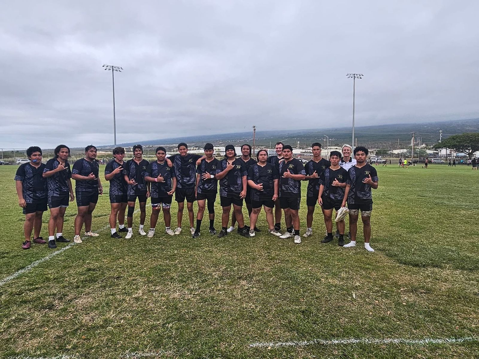 Rugby team posing together in matching dark kits